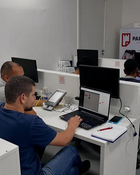 Aluno configurando um equipamento de controle de acesso no notebook, na bancada de prática